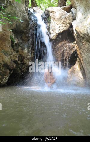 L'uomo gode di piscina presso la base della grande cascata Foto Stock