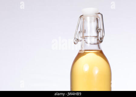 Close up di birra fatta in casa in bottiglia di vetro chiaro con una leva metallica Coperchio e fondo bianco con copia spazio. Foto Stock