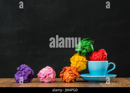 Blue caffè caldo coppa di gruppo e spazzatura rainbow paper sfere performance design stile di ispirazione pensando con forma sporchi sul pavimento in legno con il nero ch Foto Stock