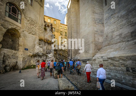 Un gruppo di turisti a piedi lungo uno stretto sentiero in pietra tra una pietra e una parete di roccia a Avignon Francia nella regione della Provenza Foto Stock