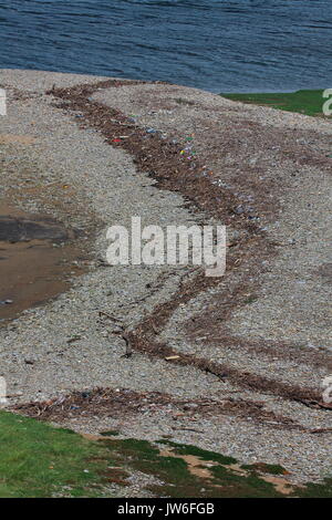 Una sventura per la campagna è tutte queste bottiglie di plastica e altri oggetti che sono stati depositati su una banca di scandole in un piccolo estuario. Foto Stock