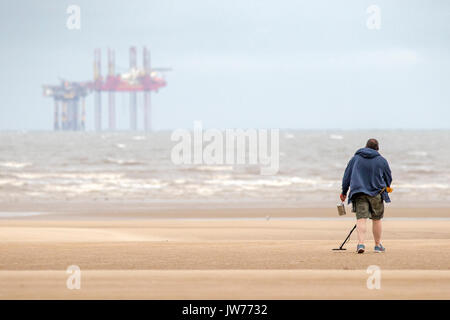 Southport, Merseyside, 12 agosto 2017. Regno Unito Meteo. Un freddo e grigio per cominciare la giornata in Inghilterra del nord ovest non si ferma un metallo detectorist a caccia di tesori sepolti sulla spiaggia a Southport nel Merseyside. Credito: Cernan Elias/Alamy Live News Foto Stock