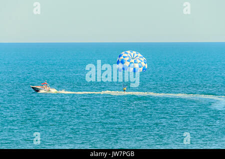 Blu ala parasail tirata da una barca in acqua di mare, Parasailing noto anche come parascending parakiting o. Foto Stock