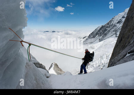 Vista posteriore di alpinista rappeling giù a San Liana sud-est. La mattina presto in Minya Konka massiccio, Daxue gamma nel Sichuan occidentale vicino al Tibet. Cina.Asia Foto Stock