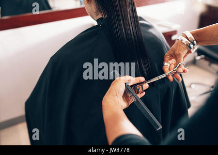 Hair stylist il taglio dei capelli di un rettilineo di livello. Parrucchiere utilizzando il pettine e forbici per un taglio di capelli. Foto Stock