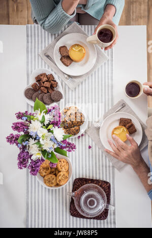 Vista aerea del giovane bere il tè mentre si consuma la colazione a casa Foto Stock