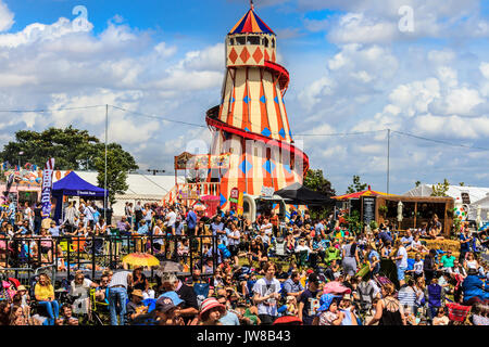 La folla raccolta vicino il cibo si spegne e area di intrattenimento, con un tradizionale Helter Skelter scivolo a spirale, Jimmy's Festival, Ipswich, Suffolk, Regno Unito Foto Stock