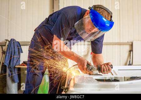 Close-up del lavoratore il taglio di metallo con la fresa. La formazione di scintille durante la rettifica di ferro. Foto Stock