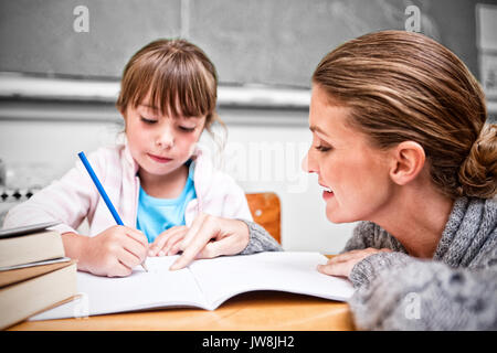 La scolaretta iscritto con il suo maestro sorridente in aula Foto Stock