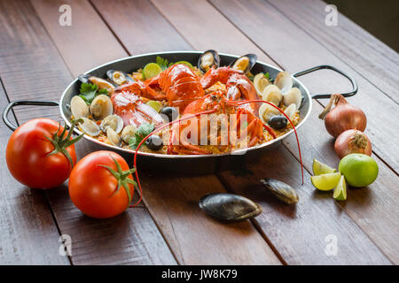 Gourmet a base di pesce paella Valencia con un fresco e langoustine, vongole, cozze e calamari su gustosa riso allo zafferano con piselli e le fette di limone, vista ravvicinata Foto Stock