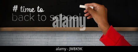 Immagine ritagliata della ragazza con la mano alzata holding chalk contro la lavagna a parete Foto Stock