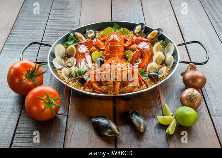 Gourmet a base di pesce paella Valencia con un fresco e langoustine, vongole, cozze e calamari su gustosa riso allo zafferano con piselli e le fette di limone, vista ravvicinata Foto Stock