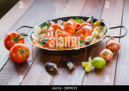 Gourmet a base di pesce paella Valencia con un fresco e langoustine, vongole, cozze e calamari su gustosa riso allo zafferano con piselli e le fette di limone, vista ravvicinata Foto Stock