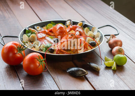 Gourmet a base di pesce paella Valencia con un fresco e langoustine, vongole, cozze e calamari su gustosa riso allo zafferano con piselli e le fette di limone, vista ravvicinata Foto Stock