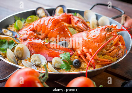 Gourmet a base di pesce paella Valencia con un fresco e langoustine, vongole, cozze e calamari su gustosa riso allo zafferano con piselli e le fette di limone, vista ravvicinata Foto Stock