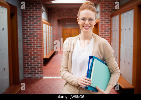 Insegnante con libri contro la parete in mattoni corridoio con pavimento piastrellato in collegio Foto Stock