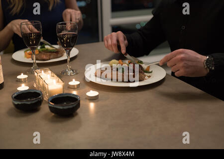 Paio di consumare la cena sul tavolo da pranzo nel salotto di casa Foto Stock
