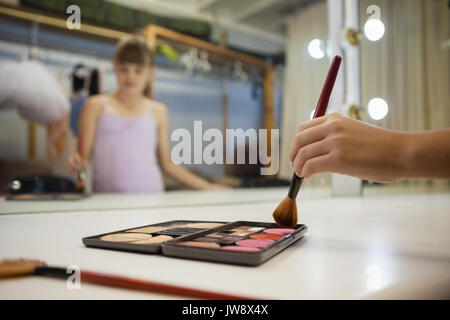 Ritagliate la mano della ragazza utilizzando arrossire mentre facendo il make up Foto Stock