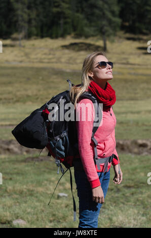 Vista laterale di un escursionista femmina con occhiali da sole in piedi sul campo Foto Stock