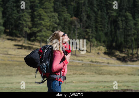 Vista laterale di un escursionista femmina con zaino cercando camminando su campo Foto Stock