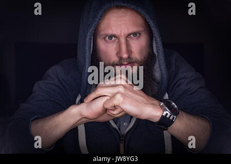 Riflessivo executive in felpa con cappuccio seduti in ufficio Foto Stock