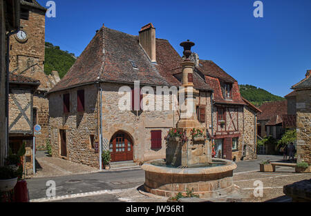 L'Europa, Francia, Occitanie, lotto,luogo di fontana nel villaggio di Autoire, rivestiti con pietra a struttura mista in legno e muratura case medievali con la chiesa romanica di San Pierre et Paul in background.i più bei villaggi di Francia Foto Stock