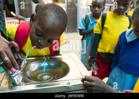 I giovani della scuola i bambini da Kibera bere dalla fontana di Kibera Town Center, Nairobi, Kenia Foto Stock