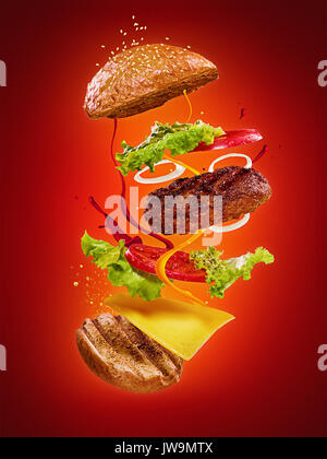 L'hamburger con battenti ingredienti su sfondo rosso. Il concetto di pubblicità Foto Stock