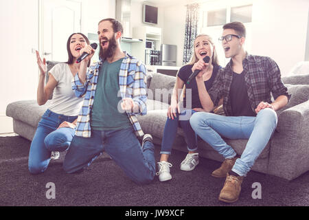 Gli amici di partito insieme al chiuso a cantare il karaoke Foto Stock