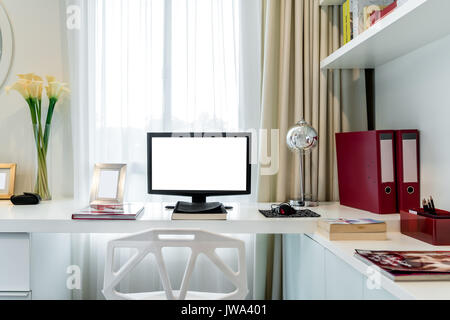 Il display del computer e gli strumenti di office sulla scrivania in casa. Computer desktop isolato sullo schermo. Moderna area di lavoro creativo dello sfondo. Spazio di lavoro a casa. Foto Stock