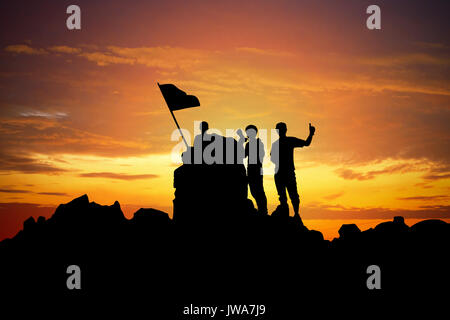 Silhouette di un campione sul picco di montagna al tramonto. Foto Stock