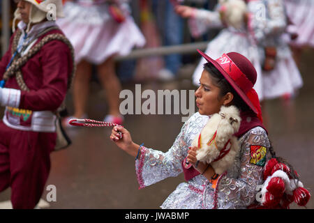 Llamerada ballerini in costumi ornati di eseguire come sfilano attraverso la città mineraria di Oruro sull'altipiano della Bolivia durante il carnevale annuale Foto Stock