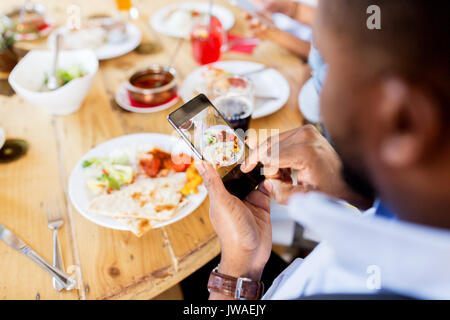 Le mani con lo smartphone dipinge il cibo al ristorante Foto Stock