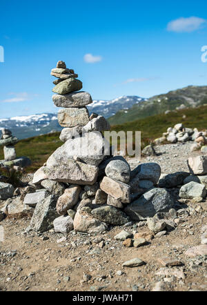 Stack equilibrata di pietre a Eidfjorden, Norvegia con la neve e le montagne come sfondo Foto Stock