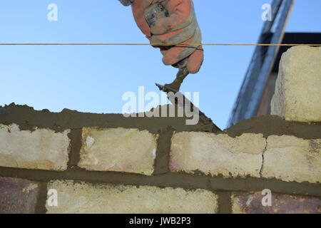 Lavoratore posando mattoni su una parete Foto Stock