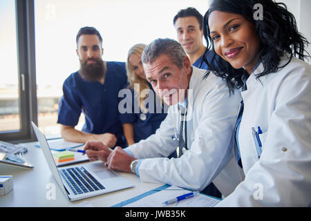 Team di multi etnico medici dell ospedale tenendo una riunione attorno a una scrivania Foto Stock