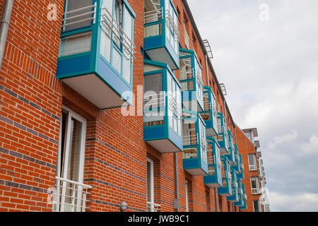 Frammento di nuova costruzione di mattoni a parete con finestre e balconi di blu. Casa appartamento moderno. Foto Stock