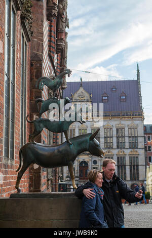 BREMEN, Germania - 16 apr, 2016: turista giovane tenendo selfie dalla famosa statua nel centro di Brema, conosciuta come la città di Brema musicisti Foto Stock