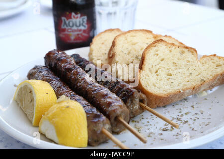 Greco cibo tradizionale, costolette di maiale con patate fritte di patate, insalata con salsa tzatziki limone e pane pita in una piastra bianca Foto Stock