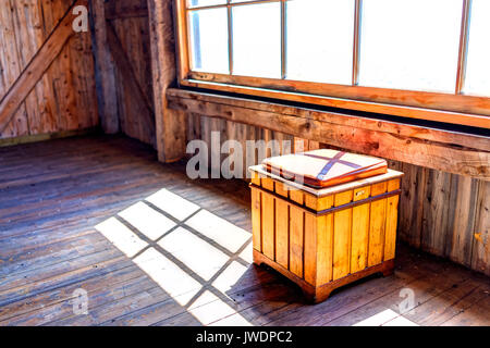 Vecchia sedia da banco dalla finestra nel vecchio casale abbandonato rustico in legno con la luce diretta del sole Foto Stock