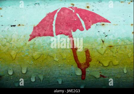 La figura di un ombrello su un tubo di ferro. La foto è stata scattata durante la pioggia e sembra che l'ombrello fonde sotto l'influenza dell'acqua. Gocce di ar Foto Stock