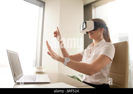 Imprenditrice eccitato in realtà virtuale bicchieri cercando di toccare Foto Stock