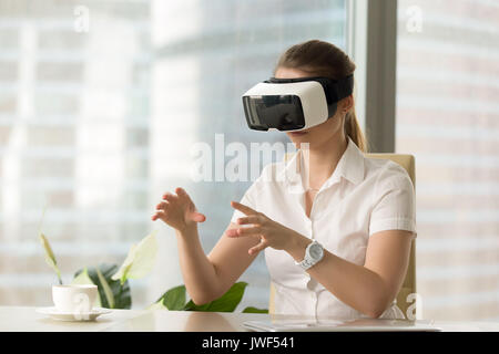 VR esperienza auricolare, curioso donna che indossa gli occhiali di protezione toccando vi Foto Stock