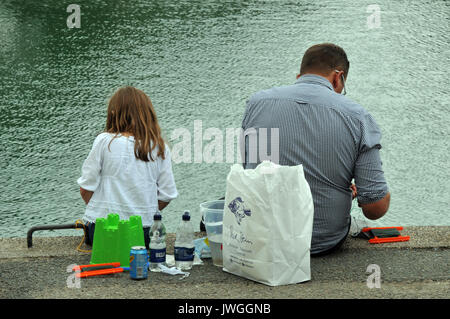 Un uomo e sua figlia seduta su una parete del porto di pesca di granchi con il loro pranzo del polmone una benna e loro esca bejind themm sul pontile Foto Stock