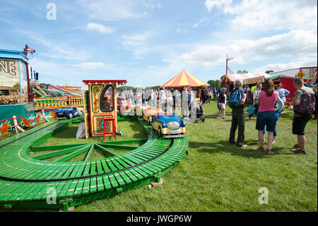 Famiglie godendo una giornata fuori al sole in un parco giochi per bambini parco di divertimenti a vapore Vintage rally, UK GB Inghilterra Foto Stock