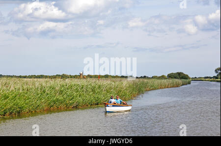 Una coppia in un piccolo gommone motorizzata sul fiume Thurne nel Parco nazionale di Broads a Martham, Norfolk, Inghilterra, Regno Unito. Foto Stock