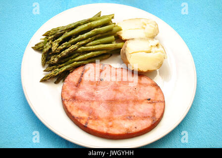 Bistecca di prosciutto servito con asparagi e patate al forno Foto Stock