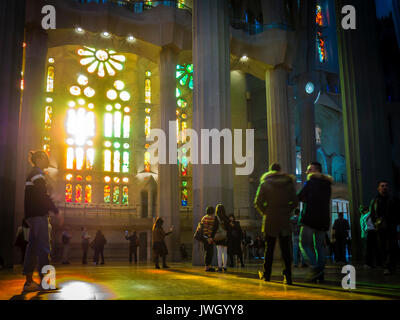 Sera La luce del sole è in arrivo attraverso le finestre verniciate della facciata occidentale di La Sagrada Familia di Barcellona cattedrale che è affollata di turisti Foto Stock