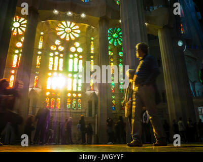 Sera La luce del sole è in arrivo attraverso le finestre verniciate della facciata occidentale di La Sagrada Familia di Barcellona cattedrale che è affollata di turisti Foto Stock