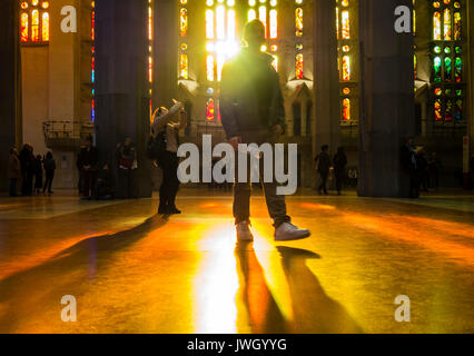 Sera La luce del sole è in arrivo attraverso le finestre verniciate della facciata occidentale di La Sagrada Familia di Barcellona cattedrale che è affollata di turisti Foto Stock